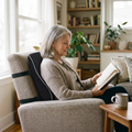 Woman reading in an armchair with a memory foam lumbar support pillow behind her back