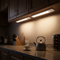Motion sensor light bars lighting a kitchen counter under the cabinets
